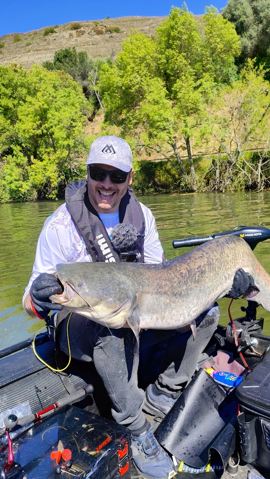 Tiago Lemos numa embarcação, segurando um peixe capturado durante uma pescaria